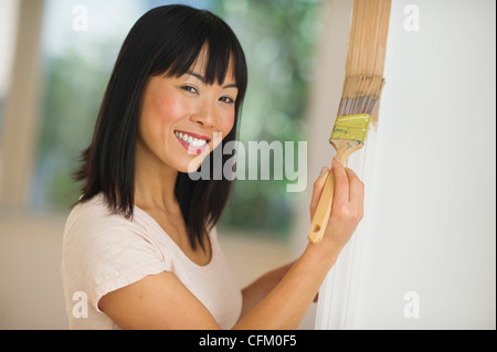 USA, New Jersey, Jersey City, Smiling woman painting cadre de porte Banque D'Images