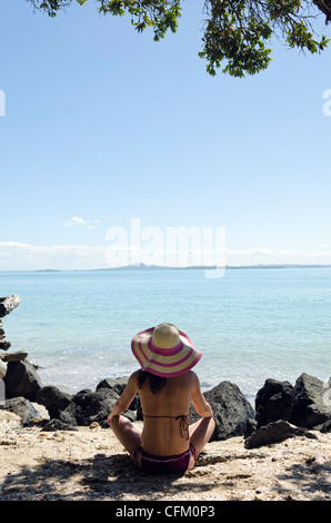 Femme assise au calme sur une belle plage wearing hat Banque D'Images