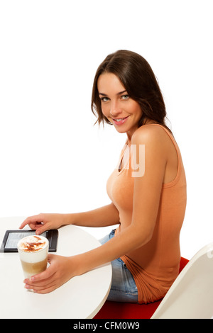 Beautiful happy woman sitting at a table avec latte macchiato et un lecteur d'ebook sur fond blanc Banque D'Images