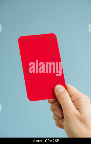 Close up of man's hand showing red card, studio shot Banque D'Images