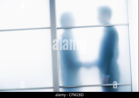 USA, New Jersey, Jersey City, les silhouettes des deux hommes d'affaires derrière la porte de verre Banque D'Images