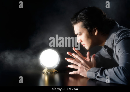 Studio shot of businessman looking at crystal ball Banque D'Images