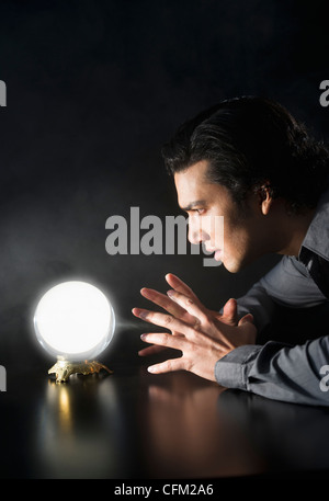 Studio shot of businessman looking at crystal ball Banque D'Images