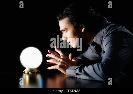 Studio shot of woman staring at crystal ball Banque D'Images