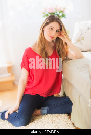 USA, New Jersey, Jersey City, Portrait of young woman sitting on floor in living room Banque D'Images