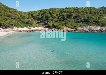 Les nageurs dans les eaux peu profondes de la plage isolée de Trebaluger sur l'île de Minorque espagne Banque D'Images