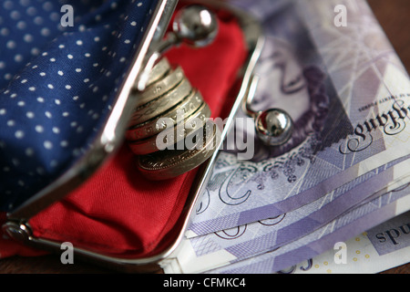 Un sac à main contenant des pièces de £1 reposant sur des notes 20 € plié Banque D'Images
