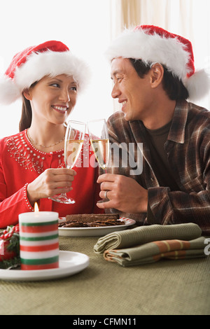 USA, Californie, Los Angeles, Couple wearing santa hats toasting with champagne Banque D'Images