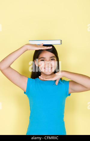 Studio portrait of teenage girl (16-17) achat de livres sur la tête Banque D'Images