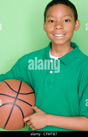 Studio shot portrait of young man holding basket ball, jusqu'à la taille Banque D'Images