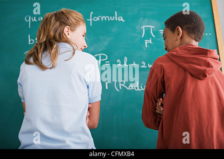 USA, Californie, Los Angeles, Girl and boy standing in front of blackboard avec formule mathématique Banque D'Images