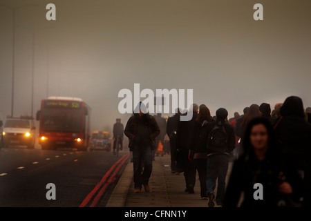 Les navetteurs et occupé le trafic traversant le pont de Londres sur un matin de smog Banque D'Images