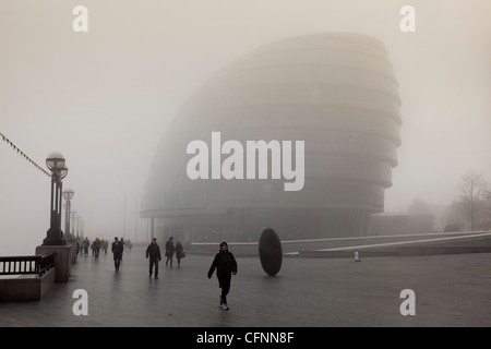 Les navetteurs en passant devant l'Hôtel de ville de Londres sur les rives de la Tamise dans le brouillard du matin Banque D'Images