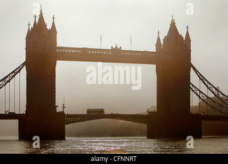 Un bus traversant le Tower Bridge dans la brume matinale de l'aube Banque D'Images