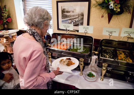 Une vieille dame qui sert elle-même de la nourriture dans le restaurant indien Tamasha, Bromley, Kent UK Banque D'Images