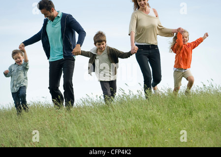 L'exécution de la famille main dans la main dans le champ Banque D'Images