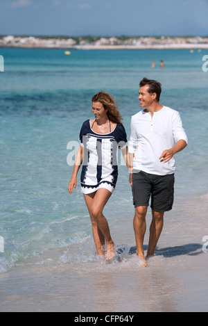 Couple walking on beach Holding Hands, les chevilles dans l'eau Banque D'Images