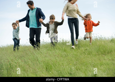 L'exécution de la famille main dans la main dans le champ Banque D'Images