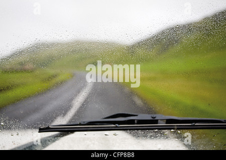 Road et la campagne vue à travers le pare-brise de voiture humide Banque D'Images