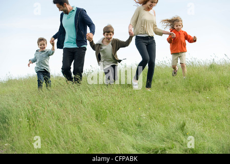 L'exécution de la famille main dans la main dans le champ Banque D'Images