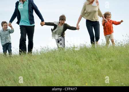 L'exécution de la famille ensemble main dans la main dans le champ Banque D'Images