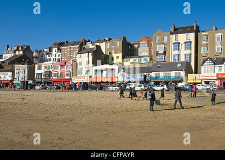 Gens touristes visiteurs sur la plage de South Bay en hiver Scarborough North Yorkshire Angleterre Royaume-Uni GB Grande-Bretagne Banque D'Images