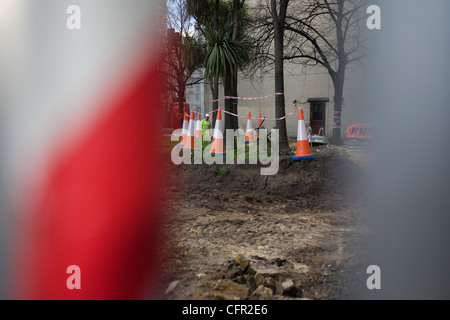 Paysage étrange façon incongrue de cônes de circulation, bande rayée et arbres urbains sur chantier de construction. Banque D'Images