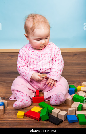 Bébé Enfant jouant avec des briques sur plancher en bois Banque D'Images