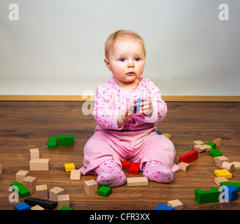 Bébé Enfant jouant avec des briques sur plancher en bois Banque D'Images