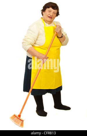 Longueur totale d'une femme âgée avec un tablier jaune cleaning broom isolé sur fond blanc Banque D'Images