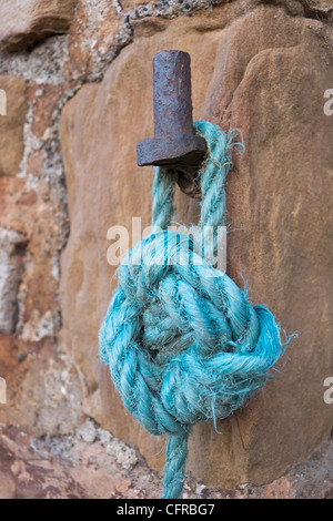 Amarre nylon bleu lié à un vieux fer à repasser fixation sur un mur du port. Banque D'Images