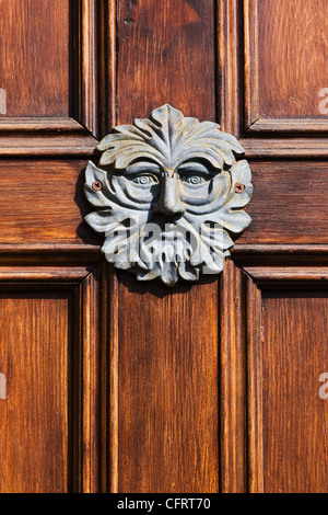 Green Man doorknocker sur une porte en bois. Banque D'Images