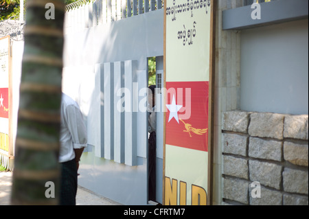 Un garde de sécurité a l'air de derrière les portes d'Aung San Suu Kyi à Rangoon accueil Banque D'Images