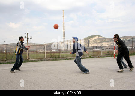 18 avril 2007 - Copsa Mica, Transylvanie, Roumanie - Jouer au basket-ball à haute cour de l'école avec l'arrière-plan usine Sometra plomb. Copsa Mica, petite ville de Transylvanie était considéré comme l'un des cinq pires sites industriels pollués du monde communiste. Une fonderie de zinc et une usine de noir de carbone sp Banque D'Images