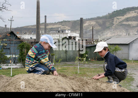 18 avril 2007 - Copsa Mica, Transylvanie, Roumanie - les enfants jouent avec le sol avec l'arrière-plan usine Sometra plomb. Copsa Mica, petite ville de Transylvanie était considéré comme l'un des cinq pires sites industriels pollués du monde communiste. Une fonderie de zinc et une usine de noir de carbone vomi heav Banque D'Images