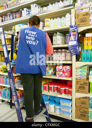 Mar 08, 2005 ; Laguna Niguel, CA, USA ; femmes femme employée worker wearing 'Que puis-je faire pour vous ?' shirt à Wal Mart stocking Walmart dans le sud CA avec étagères en laissant les acheteurs avec des sacs et des chariots chargés. Wal-mart's meilleurs prix en ont fait la plus grande chaîne de supermarchés. Banque D'Images