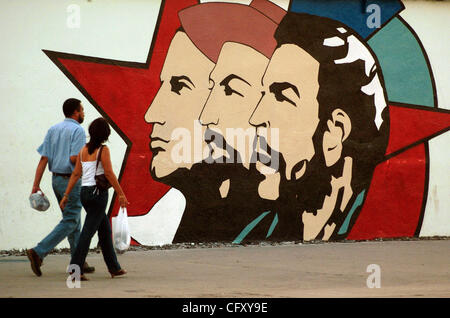 29 avr 2007 - La Havane, Cuba - Deux cubains à pied dans marchstep passé une murale de révolutionnaires Julio Antonio Mella, Camillo Cienfuegos et Ernesto 'Che' Guevara sur 'Paseo de Marti' (Marti Road) dans la vieille Havane. Les trois hommes sont bien connus aux Cubains qui la révolution dans l'étude en détail l'école alors que la plupart des Banque D'Images