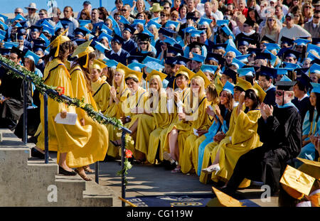 Le port de bouchons et de blouses, de deux high school catégorie senior co-valedictorians sont acclamés par les membres de la classe après avoir parlé à des diplômes à Huntington Beach, CA. Les blouses jaunes indiquent les étudiants d'élite sur le plan scolaire avec une moyenne de 4,0 ou plus. Banque D'Images