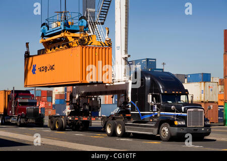 Un pont roulant spécialisé un conteneur de fret maritime gauches d'un camion à charger sur un cargo en attente à un centre de conteneurs à Jersey City, New Jersey. Banque D'Images