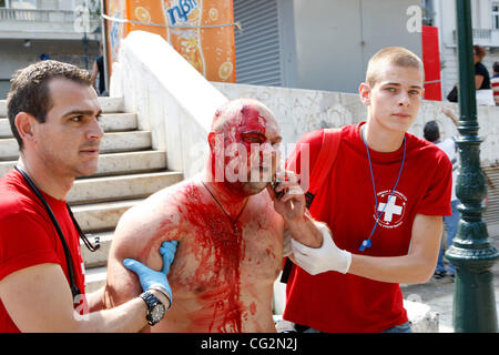 5 octobre 2011 - Athènes, Grèce - un ambulancier vient en aide à un manifestant blessé lors d'affrontements à l'extérieur du parlement grec. Grève générale de la fonctionnaires paralyse le secteur public à une manifestation plus en plus profondément les mesures d'austérité appliquées en tant que le gouvernement s'efforce d'éviter un défaut catastrophique. Banque D'Images