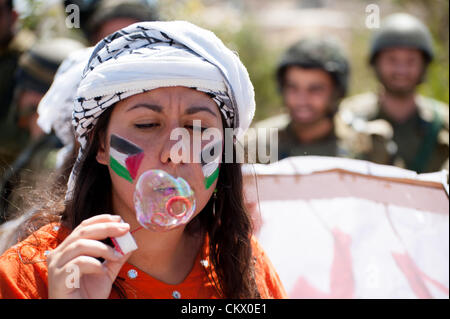 AL MA'SARA, CISJORDANIE - 24 août 2012 : les militants de la solidarité italienne inscrivez-vous palestiniens face aux soldats israéliens lourdement armés dans une manifestation non-violente hebdomadaire contre le mur de séparation qui aurait coupé le village d'al Ma'sara de ses terres agricoles. Banque D'Images