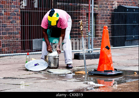 Londres, Royaume-Uni - 27 août 2012 : une femme portant un drapeau jamaïcain lave la vaisselle dans les rues pendant le carnaval de Notting Hill. Credit : pcruciatti / Alamy Live News. Banque D'Images