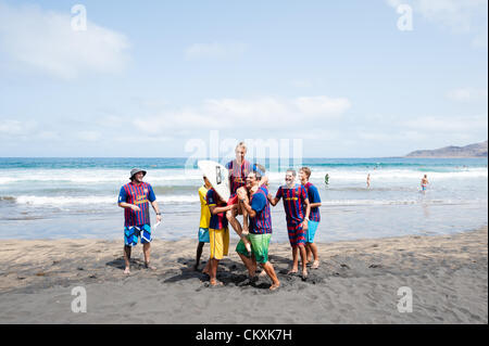 LAS PALMAS, îles Canaries, Espagne-29 août 2012 : jeunes surfeurs non identifiés de l'Université École de Surf et Surf Camp Las Palmas au cours d'une réunion informelle de la concurrence, formé comme un match de foot avec 11 surfeurs dans chaque équipe, une équipe est vêtus de T-shirts de football club F.C. Barcelone, l'autre par le Real Madrid. Banque D'Images