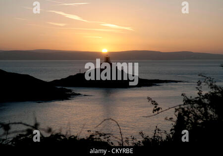 5 Septembre 2012 - Swansea - Royaume-Uni : le soleil se lève sur le phare de Mumbles (construit en 1794) dans la Baie de Swansea ce matin sur le début d'une chaude journée d'automne. Les 115 pieds de haut phare est en train d'être repeinte par it's owners Trinity House - d'où les échafaudages autour de la structure de plus de 200 ans. Banque D'Images