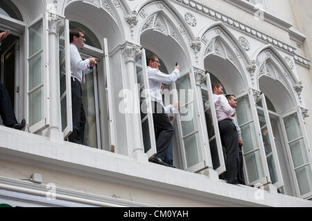 10 septembre 2012, The Strand, London. Les employés de bureau regarder la parade olympique à partir de Windows au-dessus de Starbucks. Banque D'Images