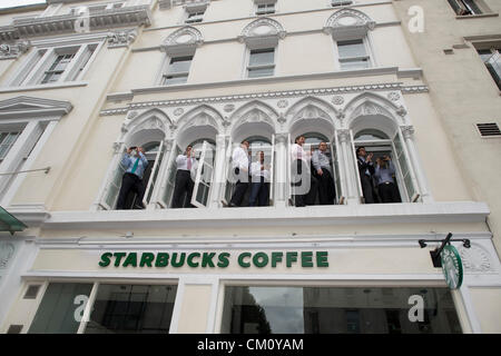 10 septembre 2012, The Strand, London. Les employés de bureau regarder la parade olympique à partir de Windows au-dessus de Starbucks. Banque D'Images