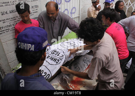 Karachi, Pakistan. 12 Septembre, 2012. Les travailleurs de sauvetage déplacer un cadavre brûlé d'un travailleur d'usine dans un hôpital à Karachi le 12 septembre 2012. Au moins 289 travailleurs ont été brûlés lors de l'incendie a ravagé une usine de vêtements à Karachi. Banque D'Images