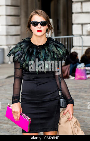 17 septembre 2012, au Royaume-Uni. London Fashion Week à Somerset House, Londres. La célèbre et assister à la mode montre ou purement pour traîner dans la cour.femme en robe noire avec des plumes et rose sac d'embrayage. Banque D'Images