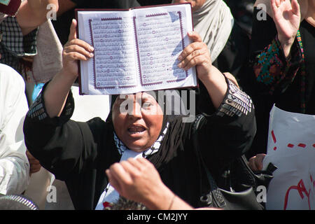 Une femme tenant et en affichant un Coran crie des slogans contre Israël et les États-Unis pour avoir prétendument comploté pour insulter les musulmans avec 'l'innocence des musulmans" film. Jérusalem, Israël. 21-Septembre-2012. Des milliers de fidèles d'Al-Aqsa se disperser tranquillement après la prière du vendredi à la Porte de Damas. Un petit groupe d'une centaine d'une étape symbolique, dix minutes, de protestation contre "l'innocence des musulmans' film insultant Mahomet et partisans. Banque D'Images