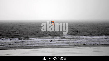 Porthcawl - UK - 3 octobre 2012 : Un kitsurfer au repos dans la baie de Porthcawl cet après-midi profitant de la tempête alors qu'une forte pluie douche se déplace vers la terre ferme derrière lui. Credit : Phil Rees / Alamy Live News Banque D'Images